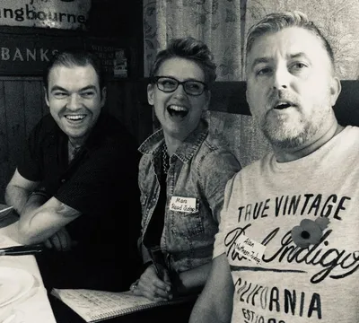 Three friends laughing together in pub